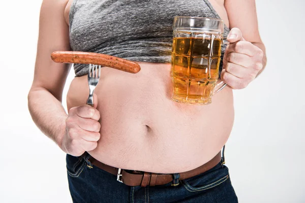 Cropped view of overweight man showing belly and holding glass of beer with grilled sausage isolated on white — Stock Photo