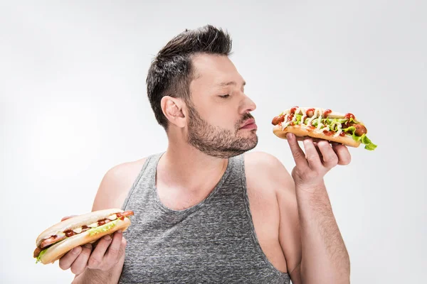 Overweight man smelling aroma of hot dog isolated on white — Stock Photo