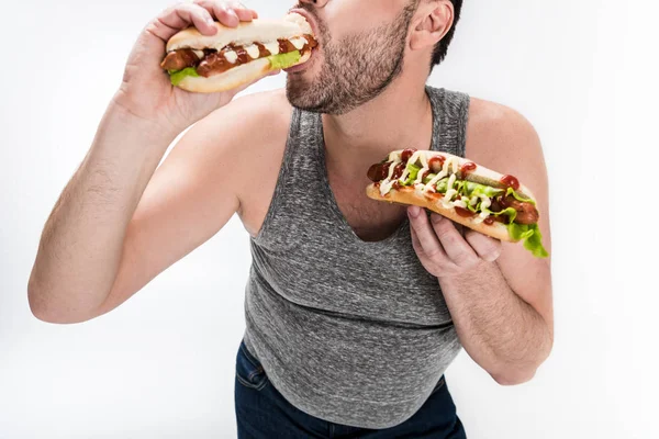 Visão cortada de homem com sobrepeso comendo cachorro quente isolado no branco — Fotografia de Stock