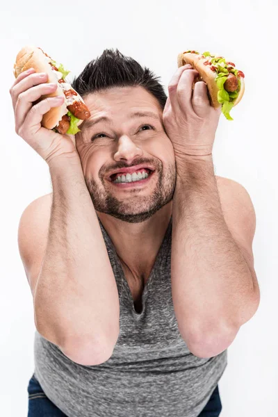 Feliz hombre con sobrepeso sosteniendo perros calientes aislados en blanco - foto de stock