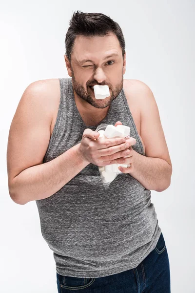 Homem com sobrepeso em top tanque cinza comendo marshmallows isolados em branco — Fotografia de Stock