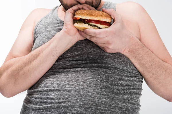 Vue recadrée de l'homme en surpoids tenant hamburger délicieux isolé sur blanc — Photo de stock