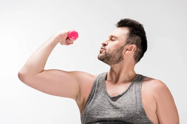 Overweight bearded man in tank top working out with pink dumbbell isolated on white — Stock Photo