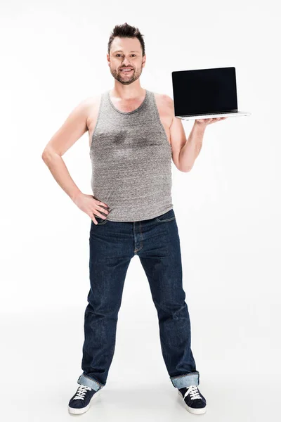 Happy overweight man looking at camera and showing laptop with blank screen isolated on white — Stock Photo