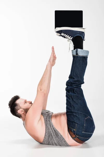 Overweight man doing abs exercise while holding laptop with blank screen on legs on white — Stock Photo