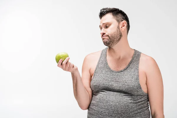 Homem com excesso de peso insatisfeito segurando maçã verde isolado no branco com espaço de cópia — Fotografia de Stock