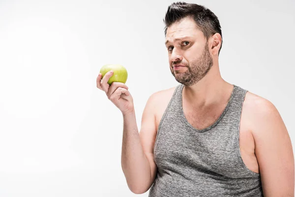 Unzufriedener übergewichtiger Mann hält grünen Apfel in der Hand und blickt isoliert auf weiße Kamera — Stockfoto