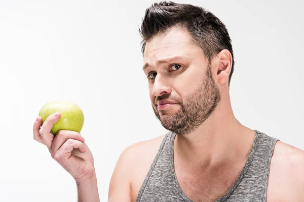 Hombre regordete insatisfecho sosteniendo manzana verde y mirando la cámara aislada en blanco — Stock Photo