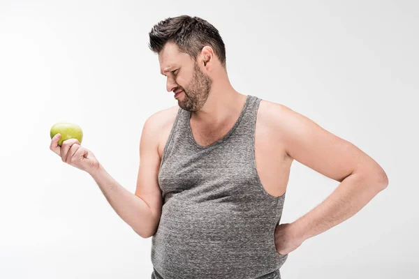 Hombre insatisfecho con sobrepeso sosteniendo manzana verde aislada en blanco - foto de stock