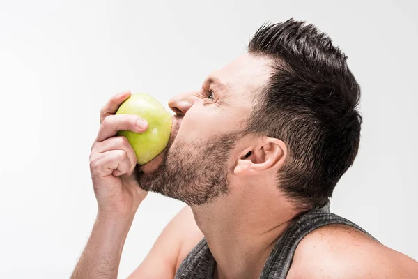 Vista laterale di paffuto uomo mangiare mela verde isolato su bianco — Foto stock