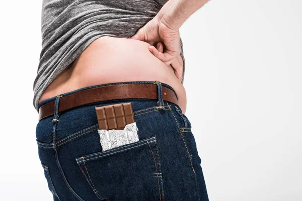 Visão parcial do homem com excesso de peso com barra de chocolate no bolso isolado no branco — Fotografia de Stock