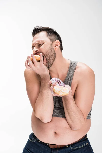 Hungry overweight man eating donuts isolated on white — Stock Photo