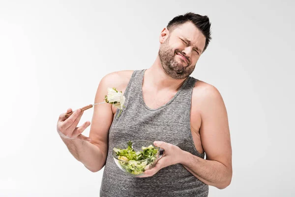 Missbilligte übergewichtigen Mann mit Schüssel Salat und machen Gesichtsausdruck isoliert auf weiß — Stockfoto