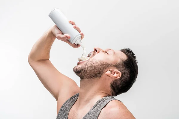 Gordinha homem no cinza tanque top pulverização chantilly na boca no branco — Fotografia de Stock