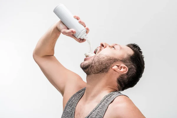 Homme potelé en débardeur pulvérisation crème fouettée dans la bouche sur blanc — Photo de stock