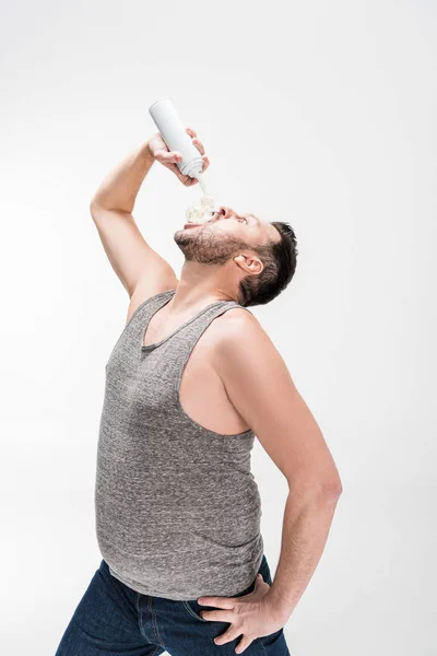 Homem com sobrepeso pulverização chantilly na boca no branco — Fotografia de Stock