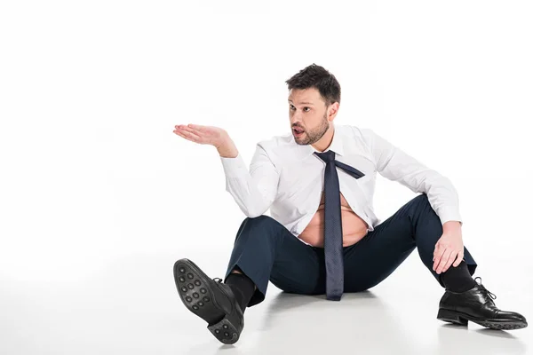 Übergewichtiger Mann in enger formaler Kleidung gestikuliert mit der Hand, während er auf Weiß mit Kopierraum sitzt — Stockfoto