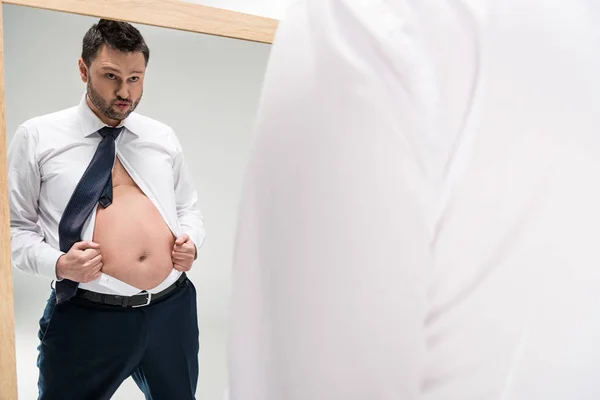 Homme en surpoids dans l'usure formelle regardant miroir isolé sur blanc avec espace de copie — Photo de stock