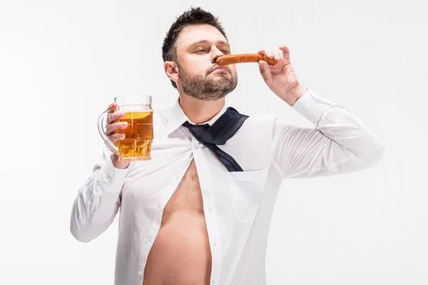 Homem com sobrepeso com olhos fechados cheiro aroma de salsicha e segurando vidro de cerveja isolado em branco — Fotografia de Stock