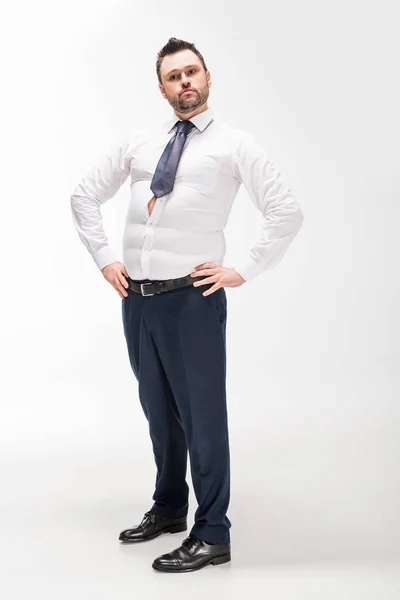 Overweight man in tight formal wear posing with hands akimbo on white — Stock Photo