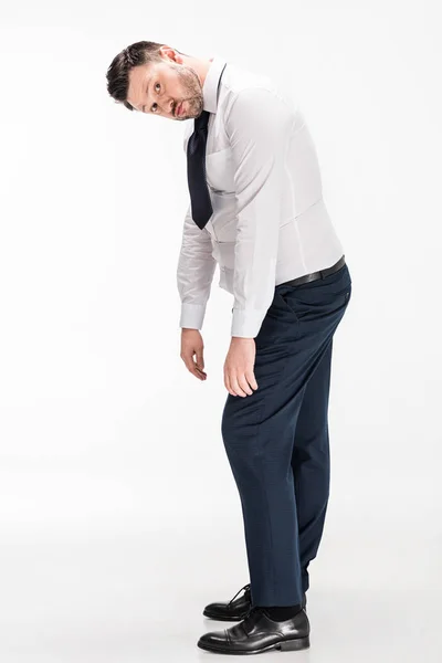 Übergewichtiger Mann in enger formaler Kleidung, der in die Kamera blickt und sich auf weiß bückt — Stockfoto