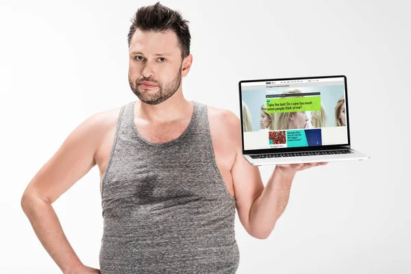 Overweight man looking at camera and holding laptop with bbc website on screen isolated on white — Stock Photo