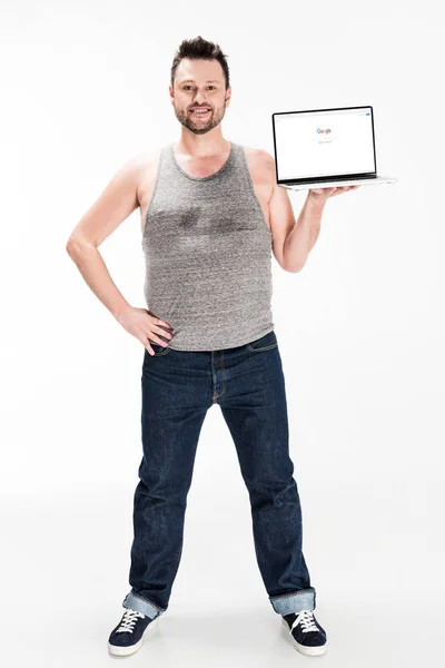Sorrindo sobrepeso homem olhando para a câmera e apresentando laptop com o site do google na tela isolada no branco — Fotografia de Stock