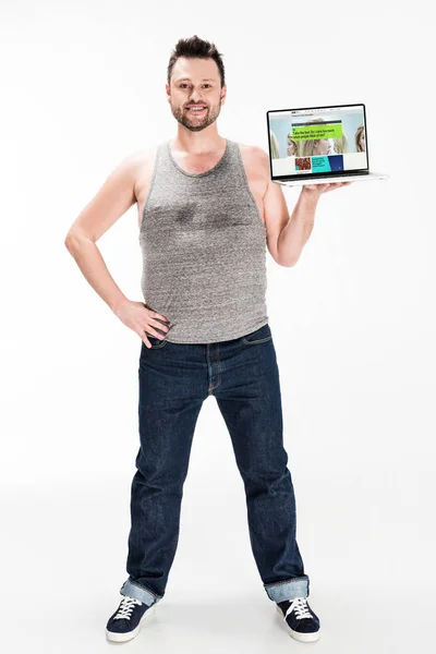 Smiling overweight man looking at camera and presenting laptop with bbc website on screen isolated on white — Stock Photo