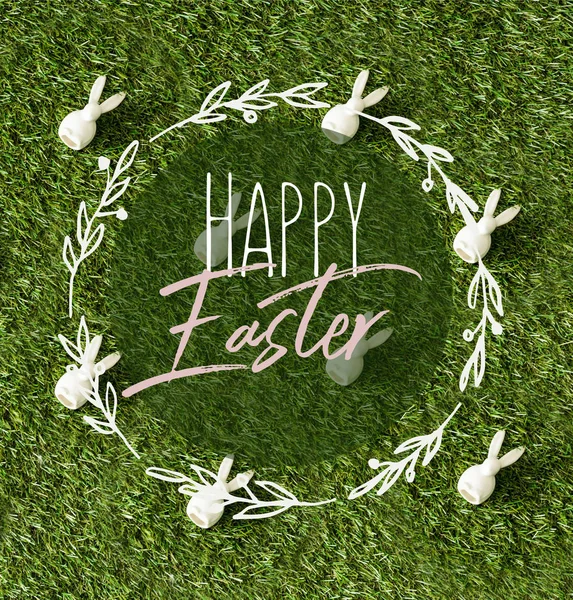 Top view of decorative bunnies scattered on green grass with happy Easter lettering in circle — Stock Photo