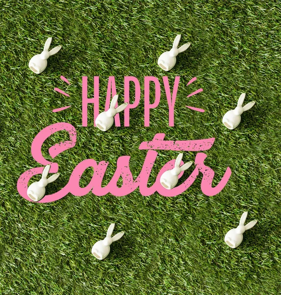 Top view of decorative bunnies on green grass with pink happy Easter lettering — Stock Photo