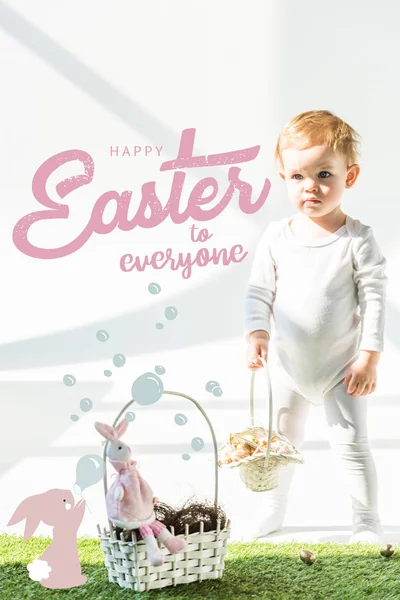 Carino babystanding con cesto di vimini su erba verde vicino uova di quaglia d'oro, buona Pasqua a tutti lettering e coniglio soffiando bolle di sapone illustrazione — Foto stock