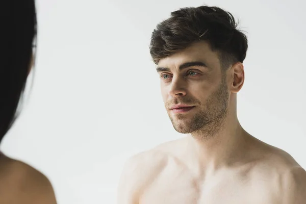 Handsome, pensive shirtless man tenderly looking at girlfriend on grey — Stock Photo