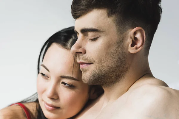 Attractive, pensive asian woman near handsome boyfriend with closed eyes on grey — Stock Photo