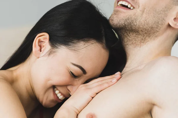 Feliz, hermosa mujer asiática acostada en los pechos de su novio sonriente - foto de stock