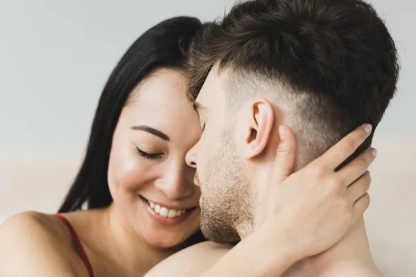 Atraente, feliz asiático mulher ternamente abraçando bonito namorado com olhos fechados — Fotografia de Stock