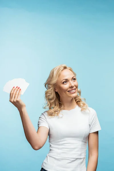 Happy blonde woman smiling while holding empty cards on blue — Stock Photo
