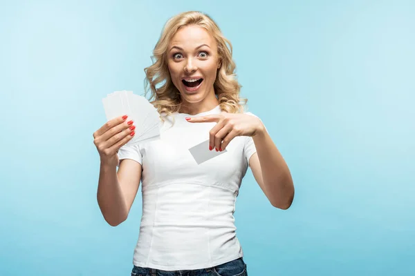 Mujer rubia excitada señalando con el dedo a las tarjetas vacías en azul - foto de stock