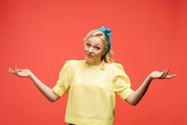 Confusa donna bionda in fascia blu in piedi e gesticolando sul rosso — Foto stock