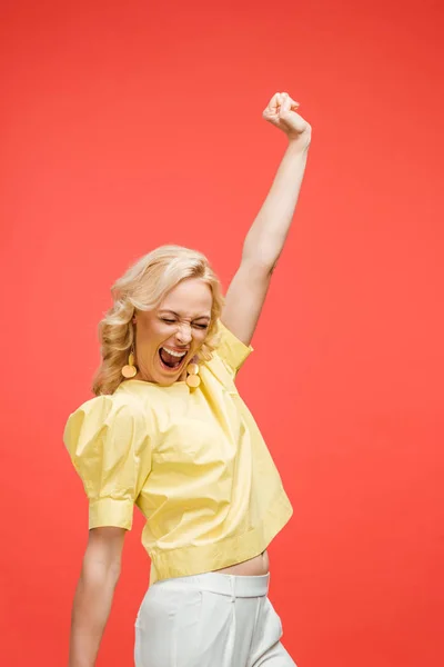 Happy blonde woman with closed eyes celebrating success on red — Stock Photo