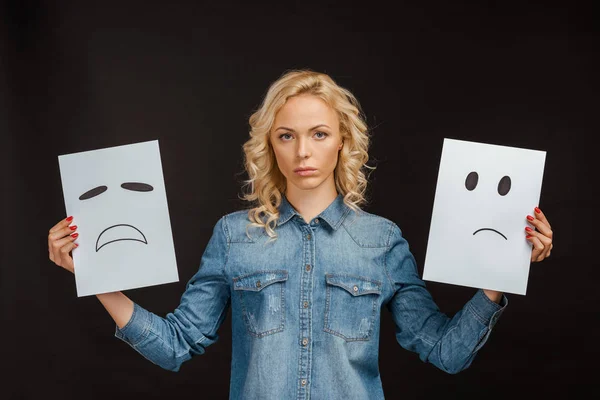 Расстроенная блондинка держит карты с грустными эмоциями на черном — стоковое фото