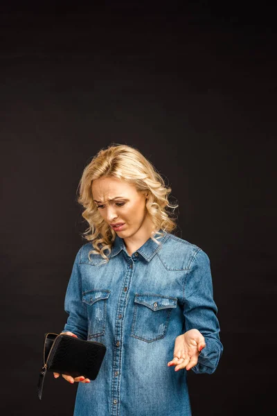 Aufgebrachte blonde Frau blickt auf leere Brieftasche und gestikuliert vereinzelt auf schwarz — Stockfoto