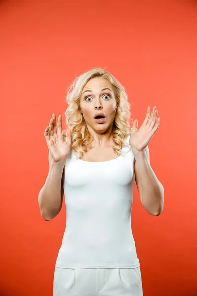 Choqué attrayant blonde femme regardant caméra et geste sur rouge — Photo de stock