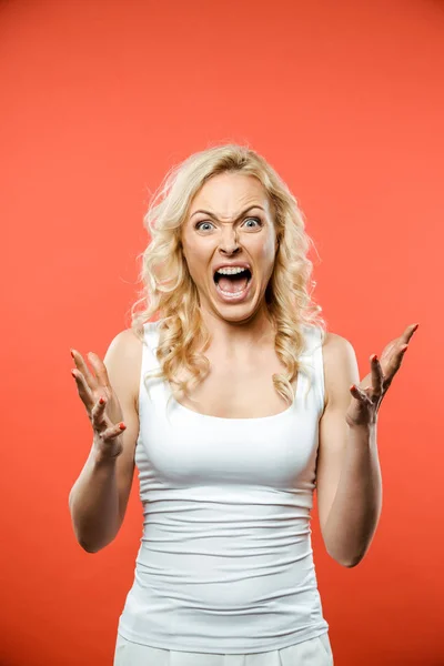 Scared blonde woman looking at camera and screaming on red — Stock Photo