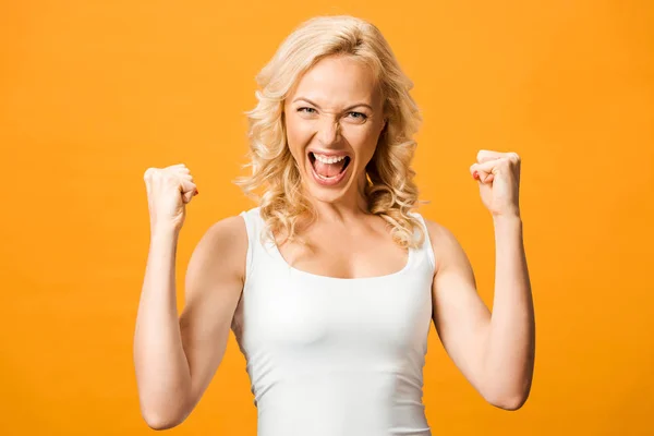 Aufgeregte blonde Frau blickt in die Kamera und feiert Triumph isoliert auf Orange — Stockfoto