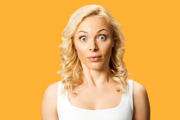 Surprised blonde woman looking at camera isolated on orange — Stock Photo