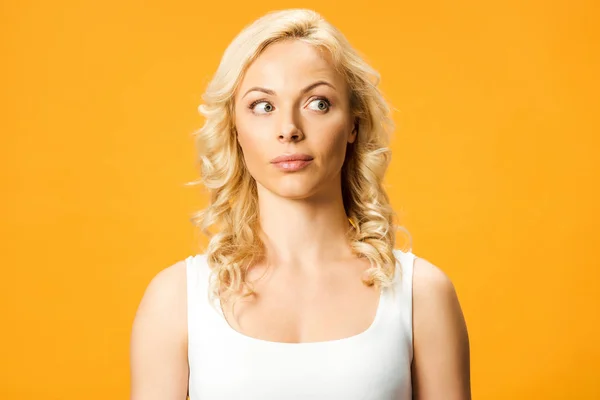 Удивленный блондинка в белой футболке изолированы на оранжевый — стоковое фото