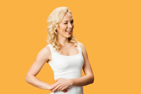 Щаслива блондинка посміхається і стоїть ізольовано на помаранчевому — стокове фото