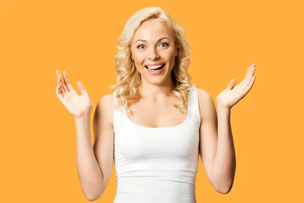 Happy curly woman gesturing while smiling isolated on orange — Stock Photo
