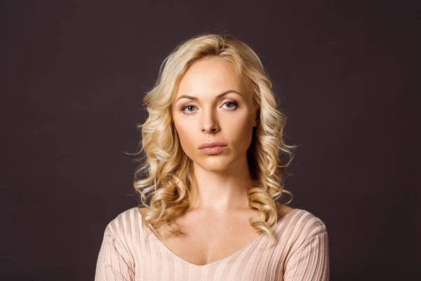 Serious blonde curly woman looking at camera isolated on black — Stock Photo