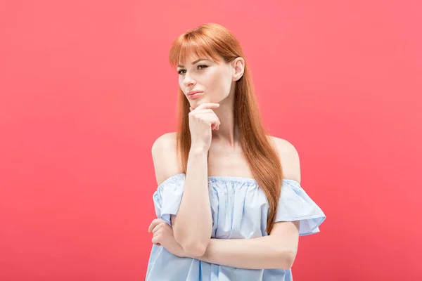 Donna rossa pensosa che tocca il mento e distoglie lo sguardo isolato sul rosa — Foto stock